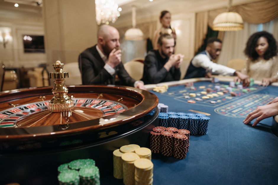 People enjoying a roulette game in an upscale casino setting with chips and a roulette wheel.